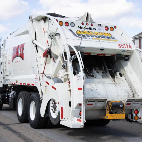 Image of a Rumpke Waste & Recycling Truck with a sanitation engineer on the back