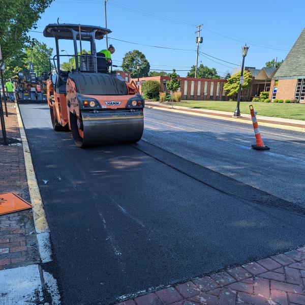 A crew from Helms and Sons Excavating paves Monroe Street as part of the 2022 paving program.