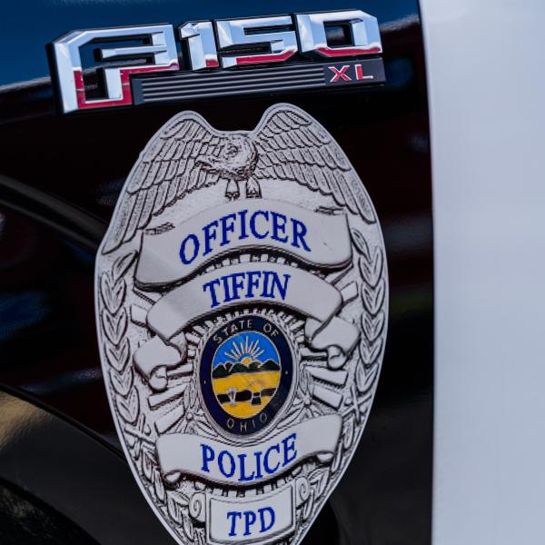 A Tiffin Police badge is shown on the side of a police vehicle